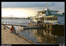 Kyjev - řeka Dněpr, kotvící loď s mileneckou dvojicí, v pozadí Pišoxidnyj mist (Пішохідний міст)